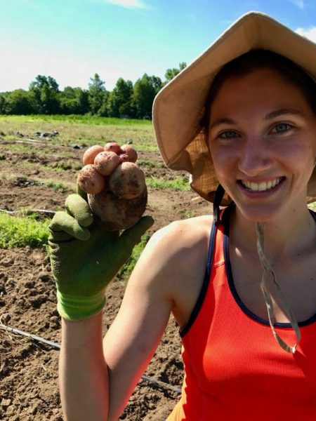 Meagan Fisher in a field, holding a vegetable.